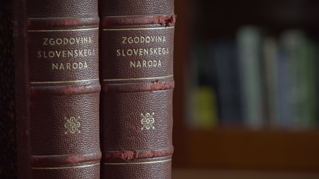 슬로베니아 국가의 역사에 관한 빨간색 표지에 세로로 놓인 오래된 책 두 권을 닫습니다.