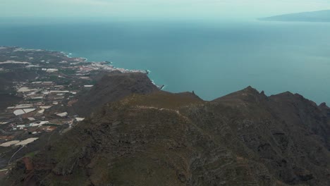 Impresionante-Toma-Aérea-En-Círculos-De-Montañas-Con-Vistas-A-Un-Hermoso-Pueblo-En-La-Ladera-De-España