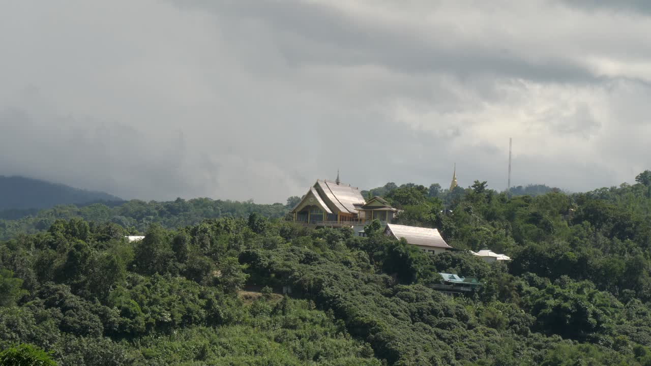 Suan Pathipatham Doi Chang-Ngu temple on a forested hill near the Thailand–Myanmar border, with dramatic skies and surrounding mountainous terrain