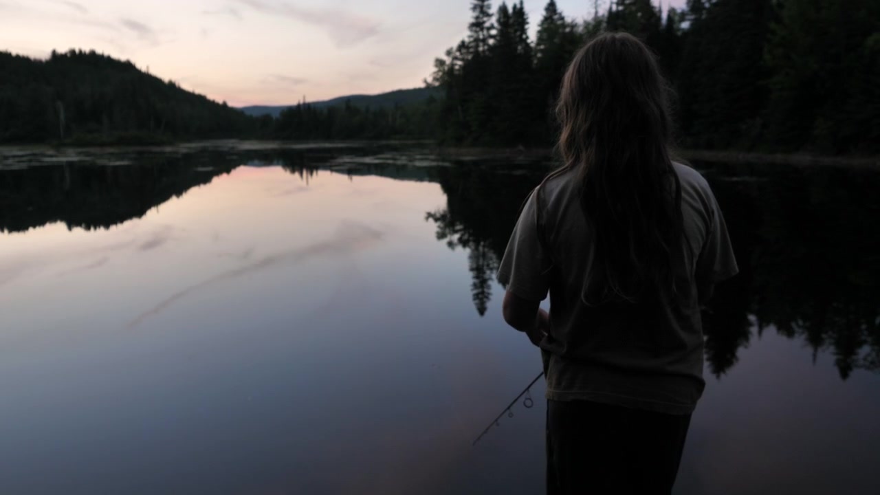 Child fishing in a lake at dawn.