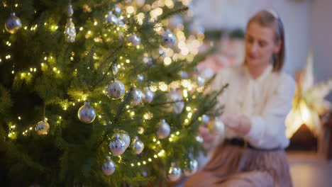 smiling woman decorates christmas tree at home and awaits guests