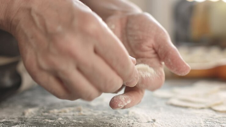 Two hands making meat dumplings.