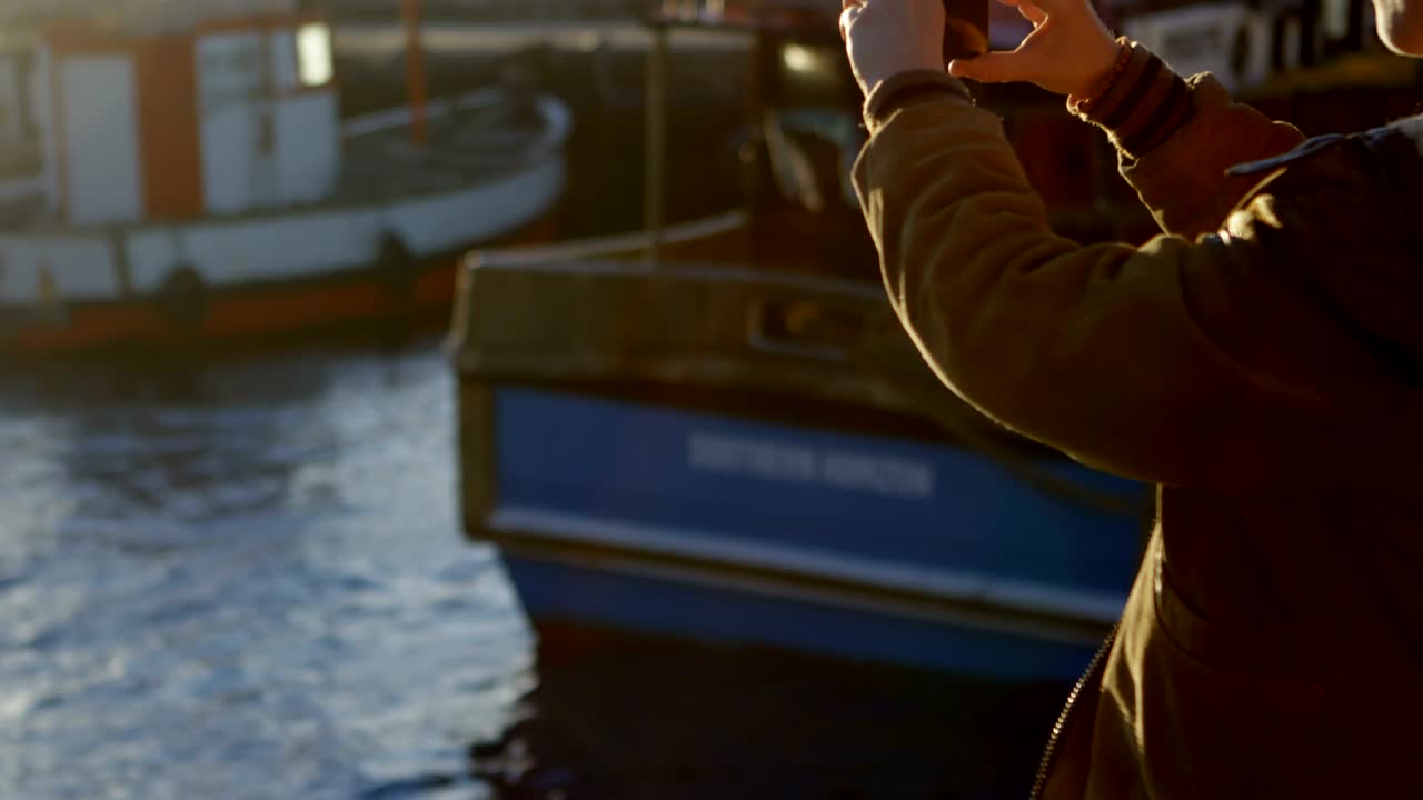 mujer haciendo clic en fotos con teléfono móvil en el muelle 4k