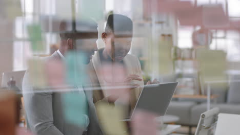 Mujer-Líder-Del-Equipo-Afroamericano-Intercambiando-Ideas-Con-Un-Colega-Empresario-Usando-Una-Computadora-Portátil-Mostrando-Ideas-Apuntando-A-La-Pantalla-Trabajando-Juntos-En-La-Oficina