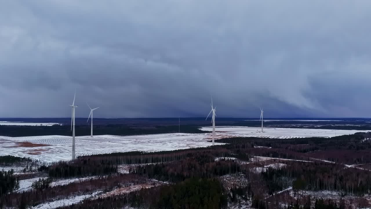Szare chmury płyną nad zimowym krajobrazem pola turbin wiatrowych