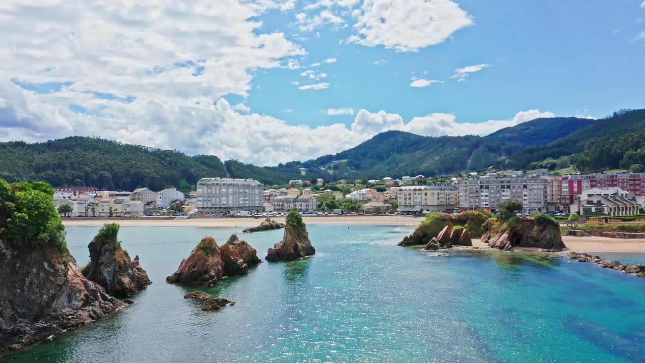 화창한 날 갈리시아 해안의 해안 마을을 향해 청록색 바다 위로 날아갑니다