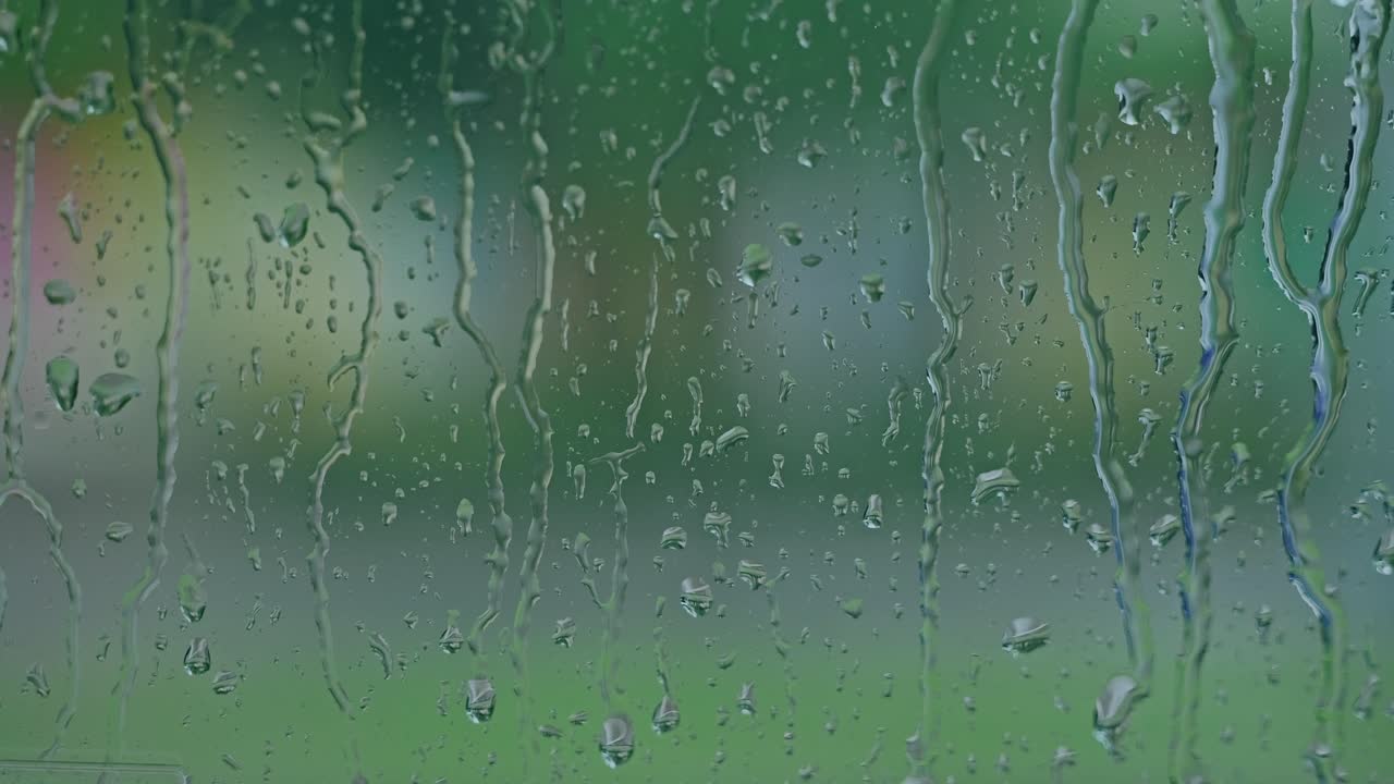 Cinematic rain on glass surface with urban background and public transport