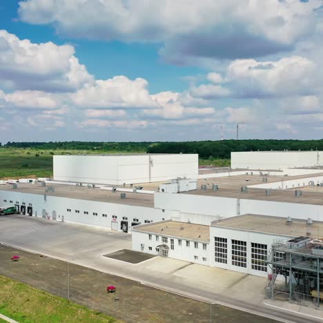 modern industry near the green forest. large territory of industrial plant in nature at sunny daytime. camera rising. drone view