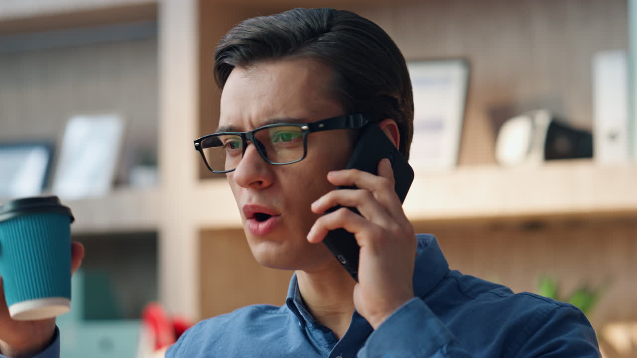 차가운 남자가 커피를 마시며 드폰으로 전화하고 프리랜서가 휴식을 즐기고 있습니다.