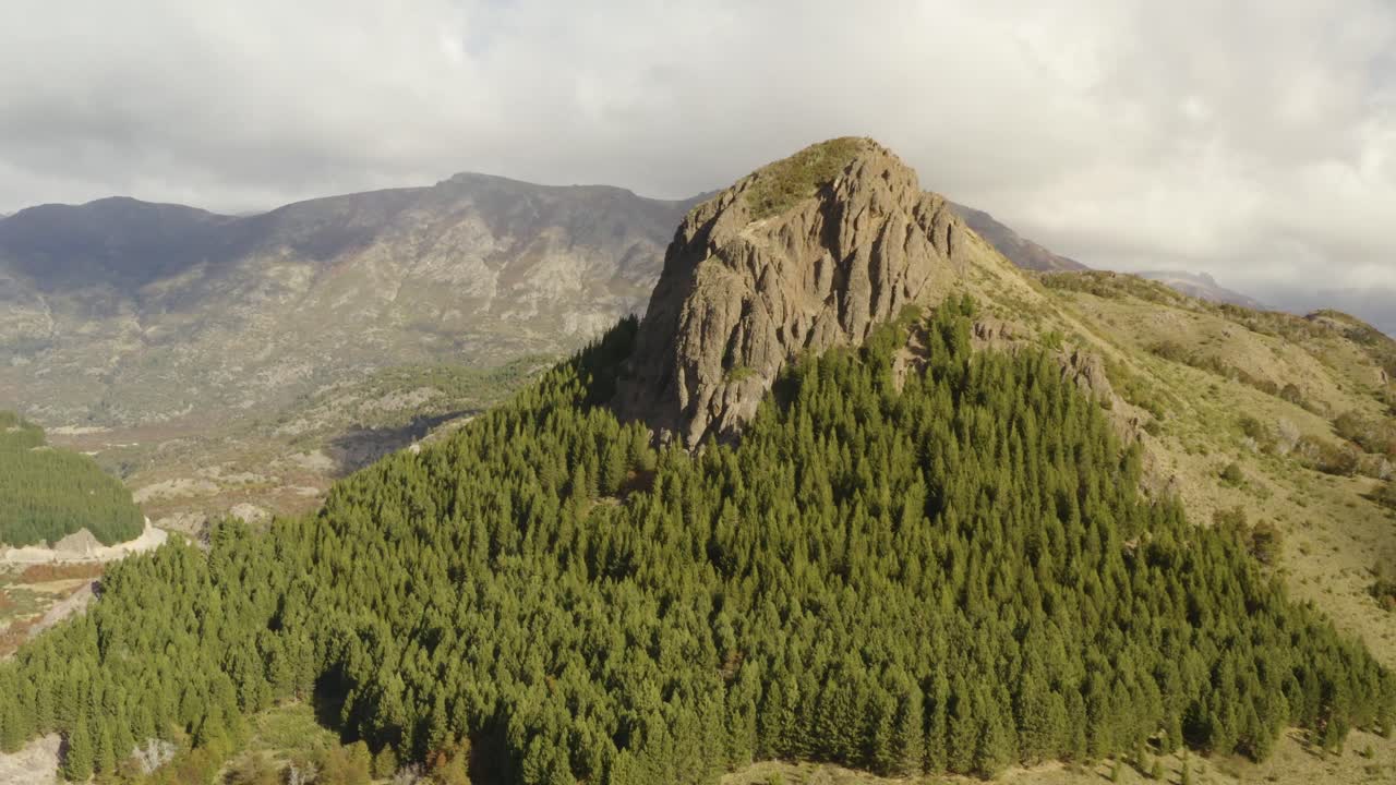 toma aérea de una montaña con una formación rocosa en la cima rodeada de bosques en la patagonia, argentina