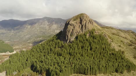 aerial shot of a mountain with a rock formation on top surrounded by woodland in patagonia, argentina