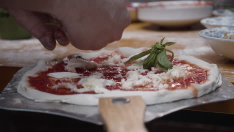 putting basil leaves on top of the neapolitan pizza dough