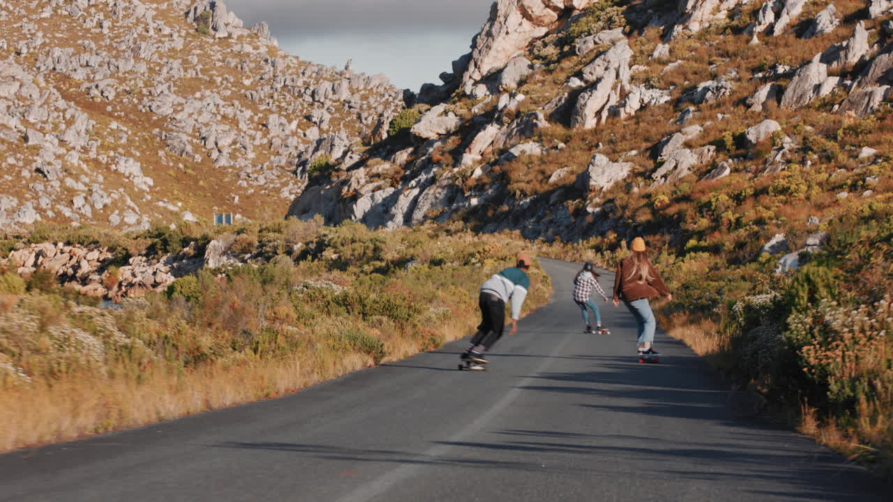 다양한 젊은 친구들이 함께 롱보드를 타고 스케이트보드를 타고 시골 도로에서 내리막길을  ⁇ 고 즐겁게 편안한 여름 휴가를 즐기고 있습니다.