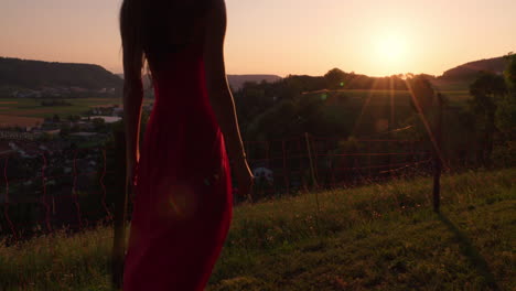 Una-Mujer-Con-Un-Vestido-Rojo-Mira-La-Puesta-De-Sol-En-Un-Paisaje