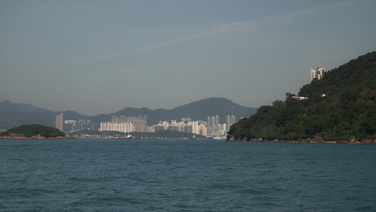 Hong Kong Harbour View from Moving Ferry of Greenery Hillsides and Dense Buildings in Daytime