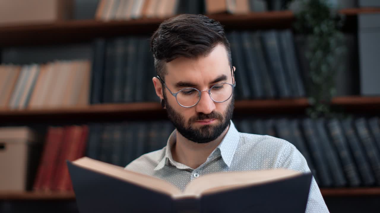 hombre barbudo moderno camisa de cuello blanco lectura vintage interesante libro de papel volviendo página en la biblioteca