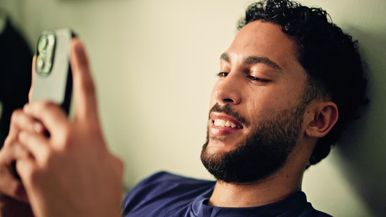 Giovane uomo che sorride e usa lo smartphone all'interno