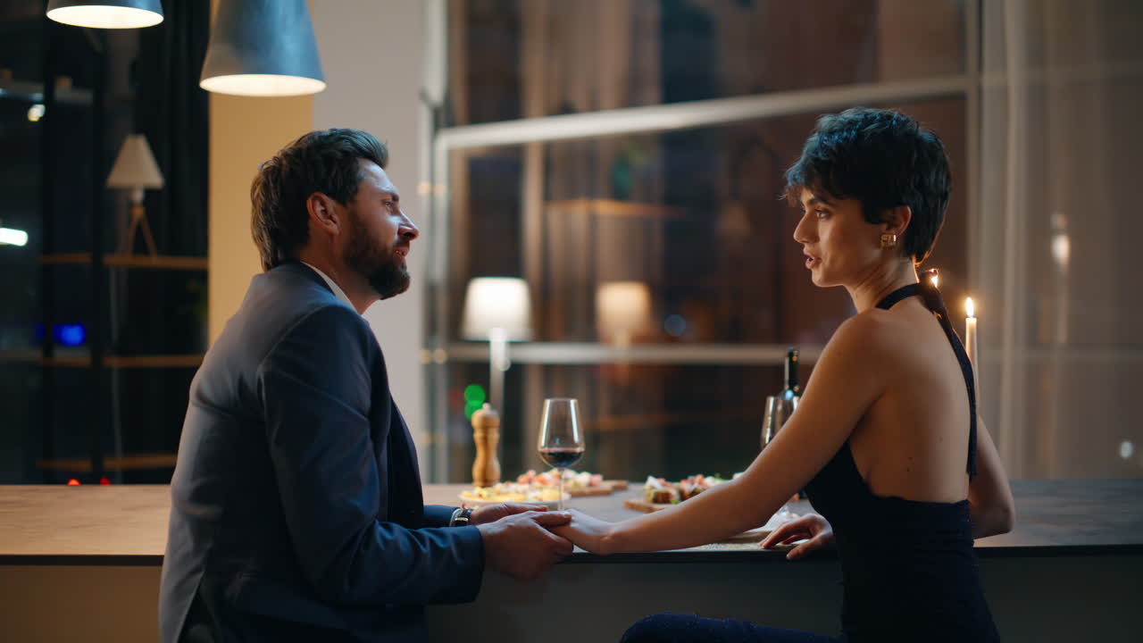 Primo piano di amanti innamorati che si tengono per mano godendosi una serata romantica insieme a casa.