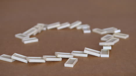 female hand toppling line of white dominoes on table