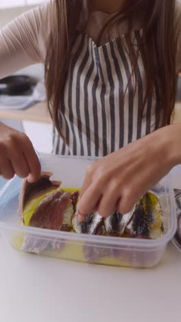Girl preparing preserved anchovies