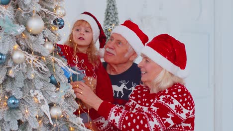 Viejos-Abuelos-Felices,-Nieta-Niño-Pequeño-Colgando-Juguetes-Decorando-El-árbol-De-Navidad-Celebrando