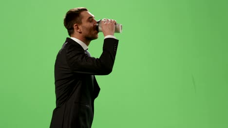 businessman in a suit is walking with a coffee on a mock-up green screen in the background.