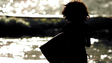 Silhouette-of-woman-holding-surfboard-and-running-on-the-beach