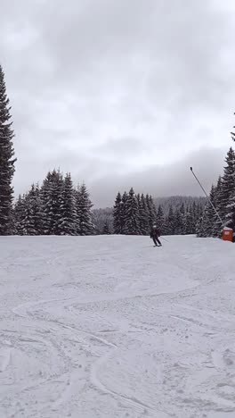 Vertical-Video-Of-Skier-Skiing-Down-Mountain-And-Covering-Camera-With-Snow