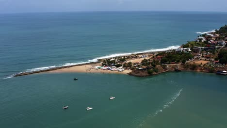 dolly in tilt-down luft-drone-aufnahme nähert sich dem tropischen berühmten tibau do sul-strand bei flut mit touristen schwimmen und genießen schatten unter bunten regenschirmen in rio grande do norte, brasilien