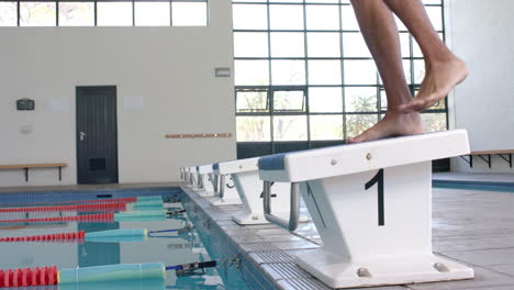 Close-up-of-a-swimmer's-feet-on-the-starting-block-at-an-indoor-pool