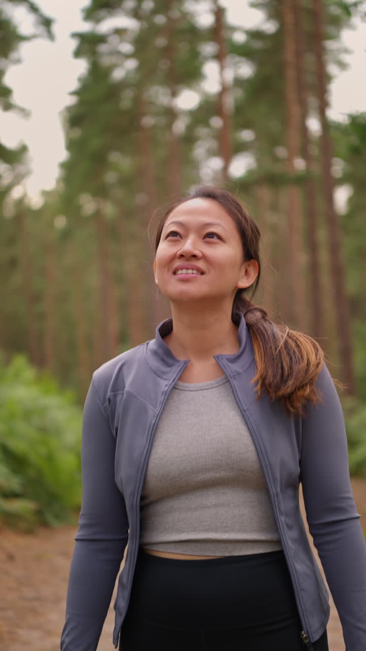 Vertical Video Of Woman Wearing Sports Clothing Exercising Looking Around Walking Along Track In Forest Enjoying Peace And Beauty Of Nature Shot In Real Time 1