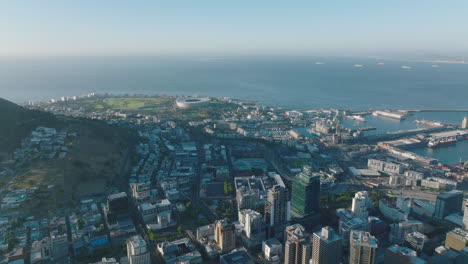 Aerial-view-of-buildings-in-city-and-sea-coast.-Slide-reveal-of-high-rise-buildings-and-seaport.-Cape-Town,-South-Africa