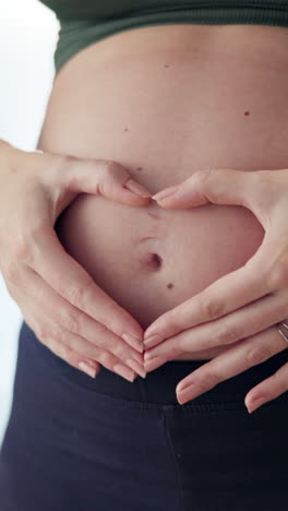 pregnant woman holding her belly in the shape of a heart