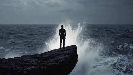 man standing on rocky coast during a storm