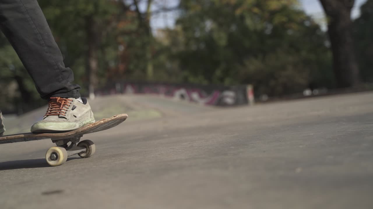 skatepark에서 야외에서 보드로 점프하고 땅을 치는 스케이트 보더의 낮은 각도 슬로우 모션 샷