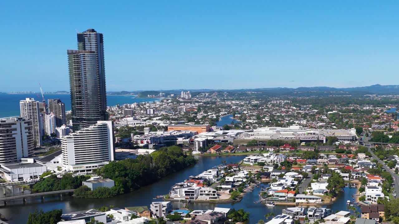 Aerial view of Gold Coast's urban skyline and waterways under clear blue skies, showcasing modern architecture and natural beauty
