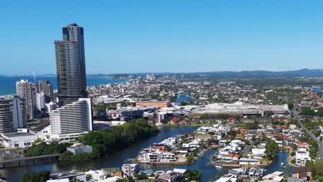 aerial view of gold coast's urban skyline and waterways under clear blue skies, showcasing modern architecture and natural beauty
