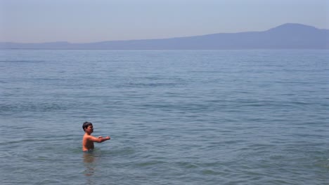 slow motion 100fps footage of two caucasian brothers , playing with a small beach ball at sea of kalamata , medium, static shot
