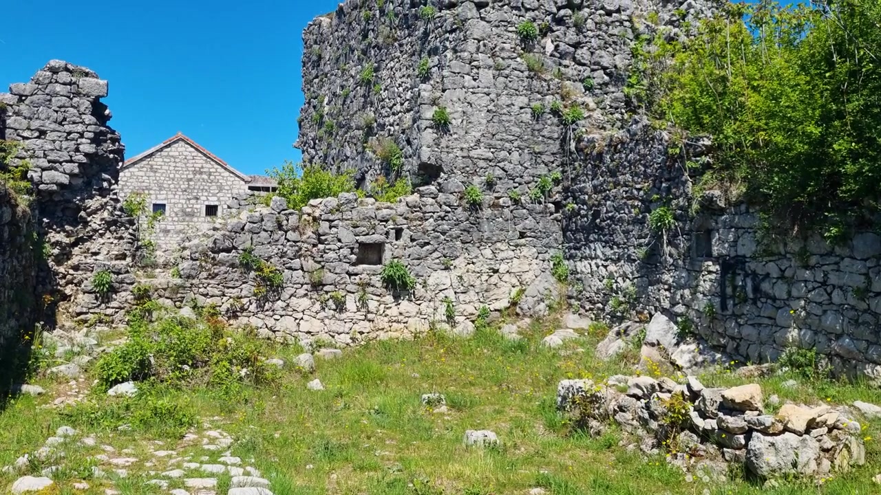 Vista all'interno della storica Fortezza di Nikšić in Montenegro, con antiche rovine in pietra sotto un cielo azzurro e limpido, che mette in mostra secoli di eredità balcanica, architettura storica e un simbolo culturale.