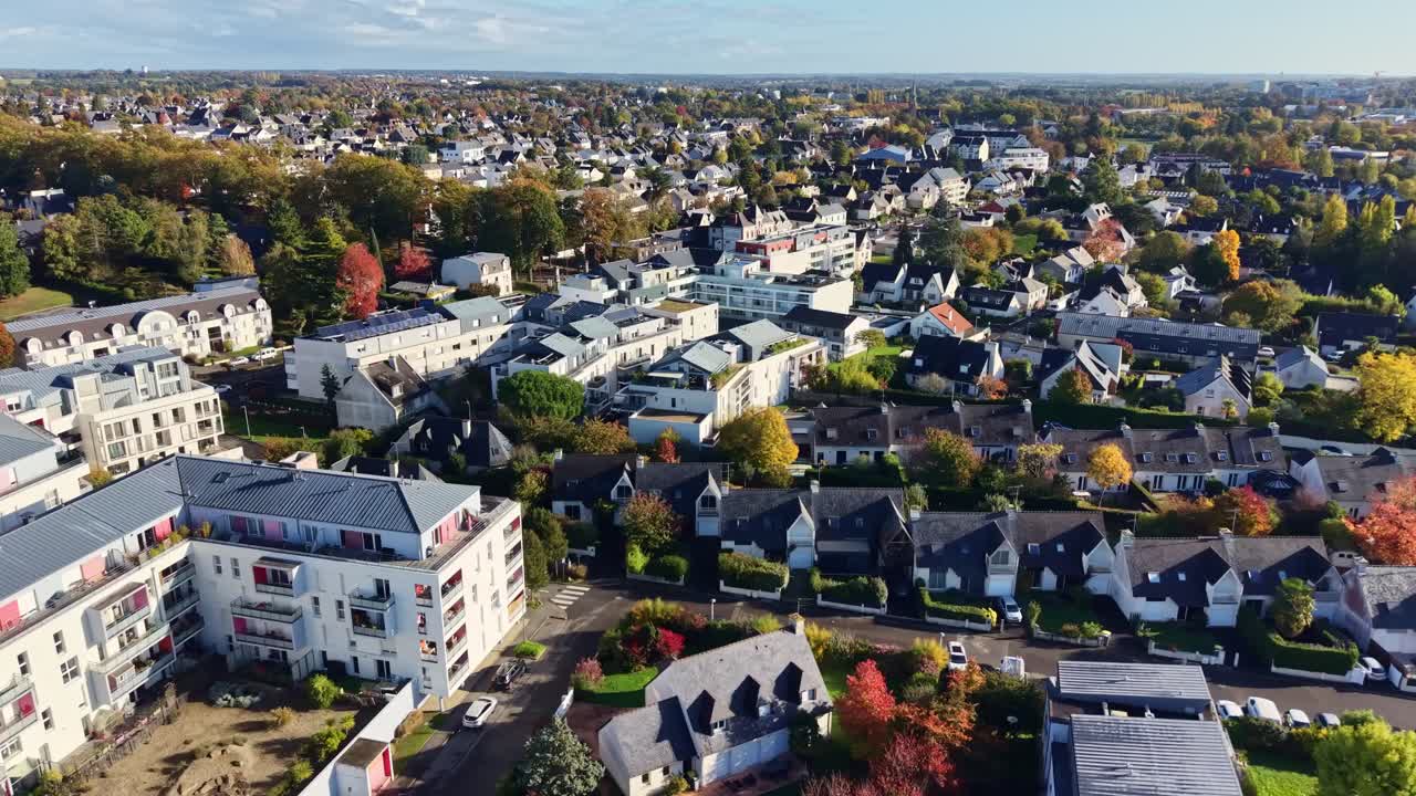 Aerial dolly above suburban neighborhood with houses, roads and trees illuminated by bright daylight, Cesson Sevigne