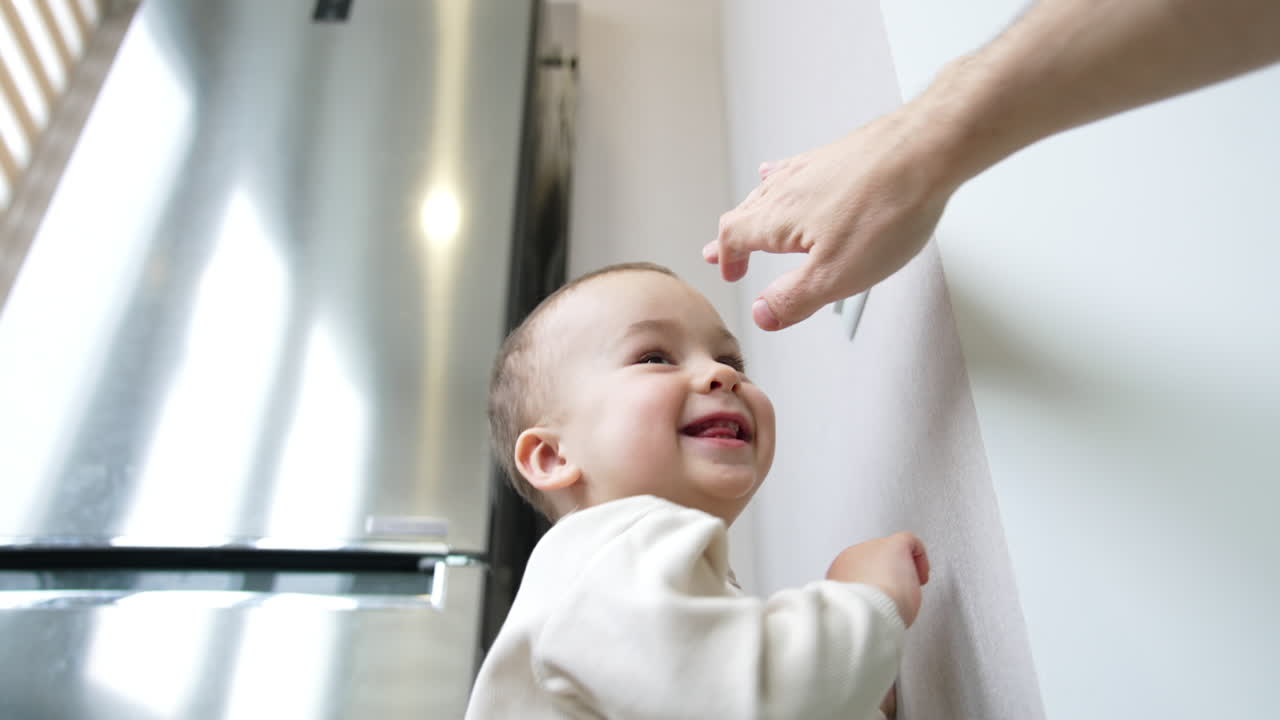 Smiley lovely boy switching on the light. Dad turns off the light. Little child playing with illumination. Low angle view.