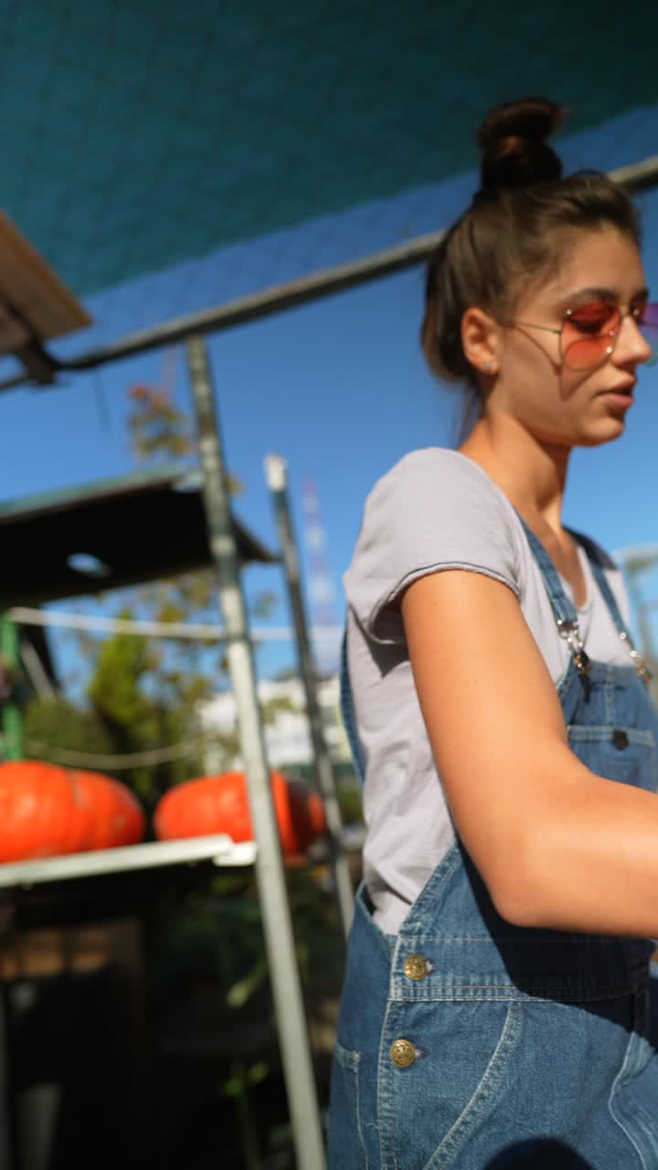 mujer joven en un mercado al aire libre, sosteniendo calabazas