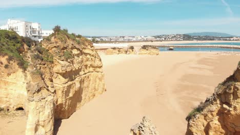 fly over sandy beach between rocks, batata beach, lagos, portugal