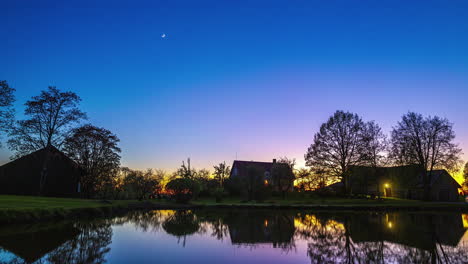 a day-to-night transition time lapse shot over a lake with cottages on the shore