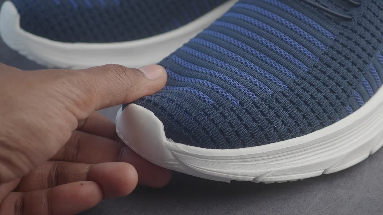 Primo piano di una sneaker blu e bianca toccata da una mano
