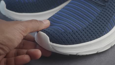 close-up of a blue and white sneaker being touched by a hand
