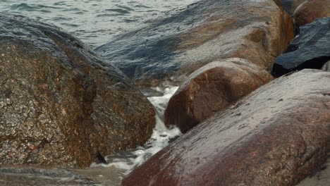 waves rolling and crashing into stones on overcast day, narrow view