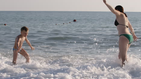 mother and son playing in the ocean waves