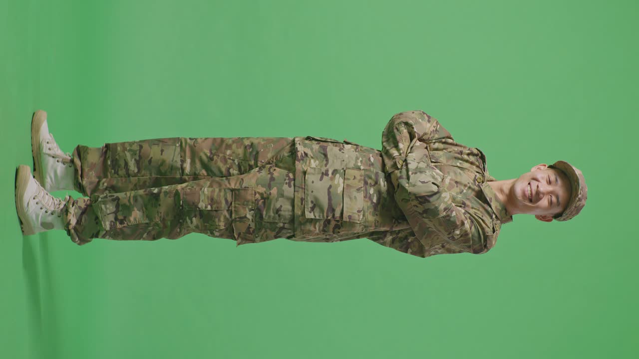 Full Body Of Side View Of Asian Man Soldier Smiling And Crossing His Arms While Standing In The Green Screen Background Studio