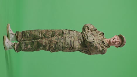 full body of side view of asian man soldier smiling and crossing his arms while standing in the green screen background studio